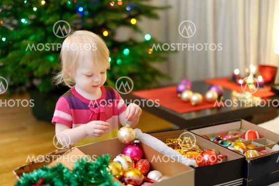 Adorable little girl decorating a Christmas tree