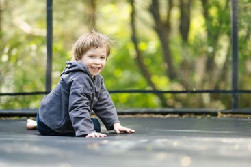 Little boy jumping on a trampoline in a backyard on warm...