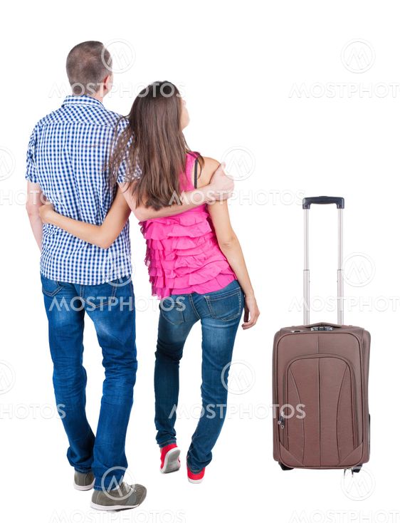 Back view of young couple traveling with suitcas .