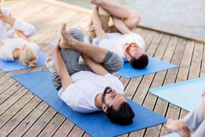 people making yoga in supine pigeon pose outdoors