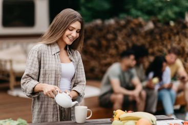 Happy millennial Caucasian woman pouring tea, making...