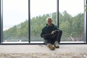 A blonde man sitting on the floor of a modern office,...