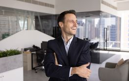 Happy CEO standing in modern office alone with hands...