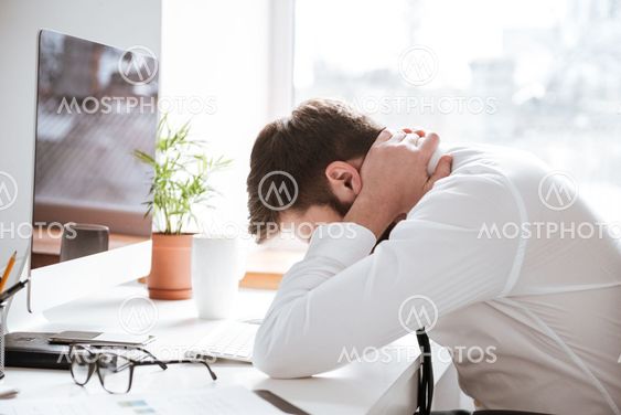 Tired young businessman with painful feelings holding neck.