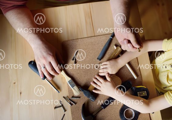 Mature man and little boy make a wooden toy together....