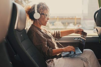 Mid age woman using computer inside transport bus...