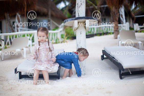 two little sisters sitting outdoor on the beach