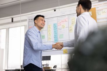 Cheerful diverse male business partners shaking hands at...