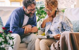Young mature couple reading together a memories book...