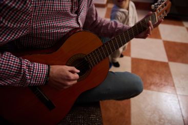 Person playing a classical guitar indoors with a...