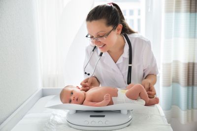 Pediatrician Checking Weight Of Baby