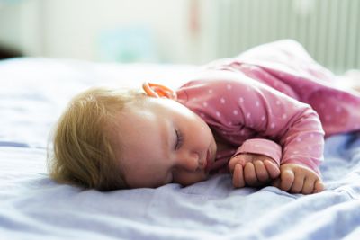 Cute little baby girl at home lying on bed, sleeping