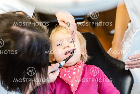Woman dentist looking after baby teeth of a little girl