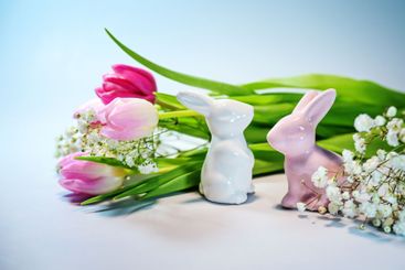 Two Easter bunnies from ceramic with a bouquet of pink...