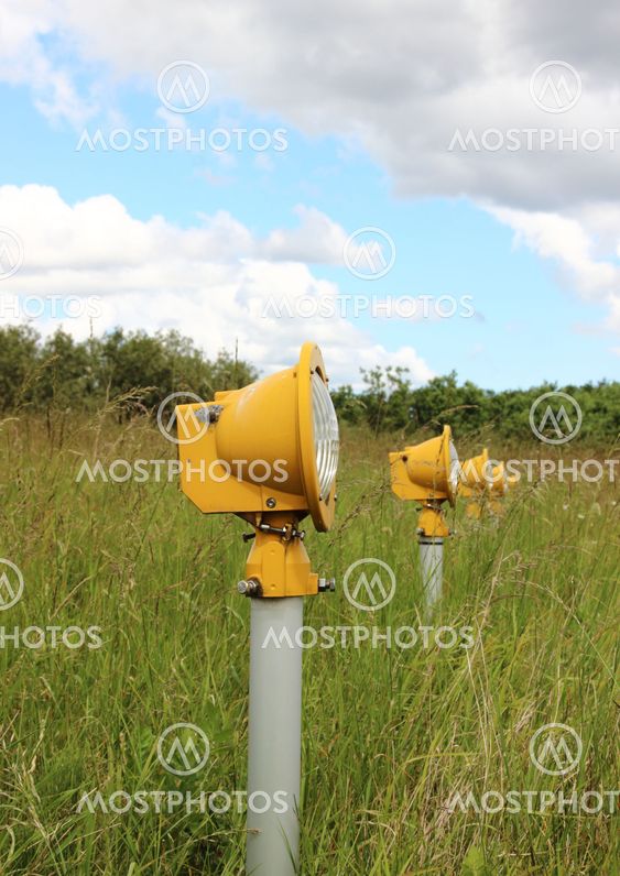 Closeup on runway landing lights in grass field