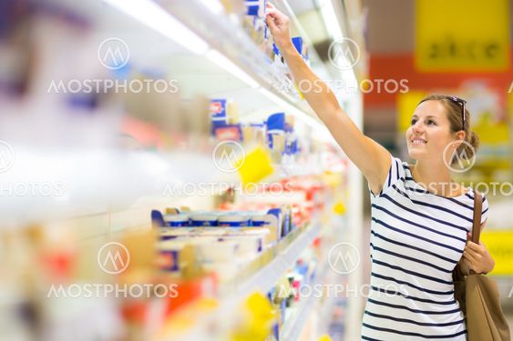 Beautiful young woman shopping for diary products at a grocery store/supermarket (color toned image)