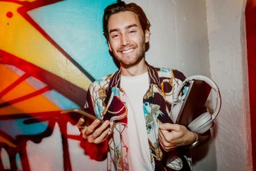 Portrait of smiling male entrepreneur holding laptop and...