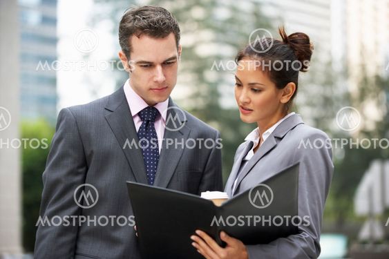 Businessman And Businesswoman Discussing Document Outside Office