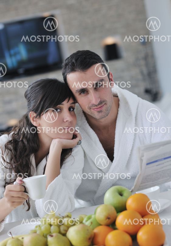 Happy couple reading the newspaper in the kitchen at breakfast