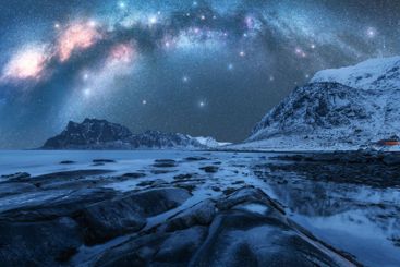 Night starry sky with Milky Way, rocky shore with stones...