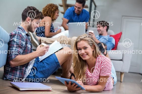 Friends using technologies while relaxing in living room