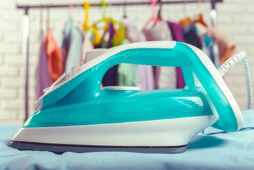 Iron on ironing board on light home interior background