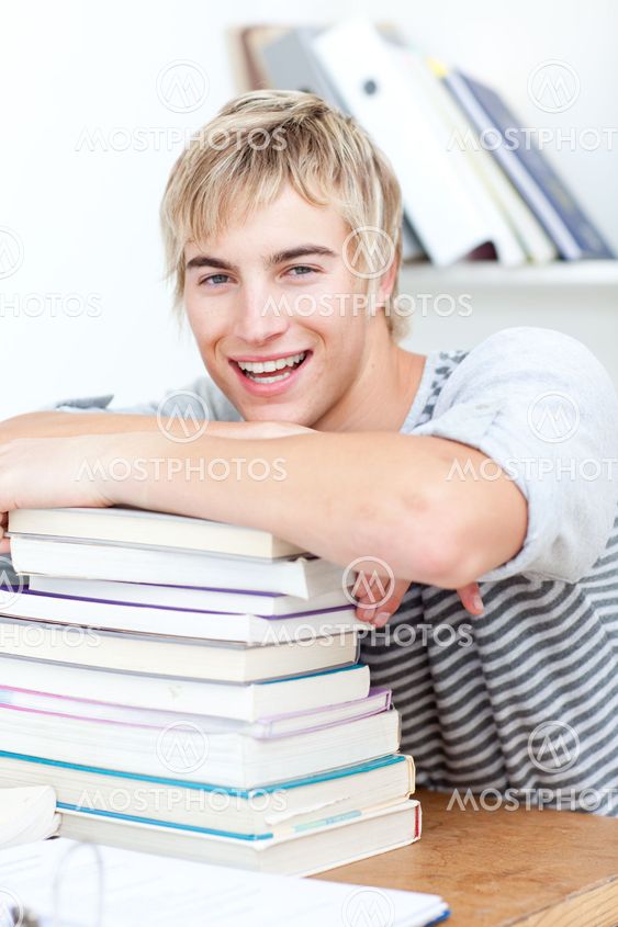 Smiling teeenager studying lots of books