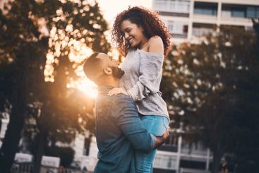 Lifting, happy and couple in park with sunshine for fun,...