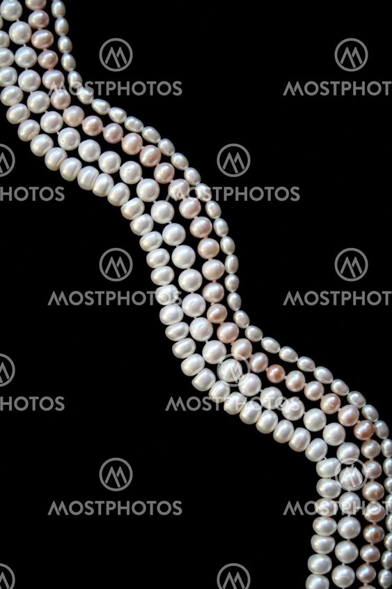 White and pink pearls on the black silk