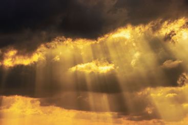Dramatic golden sunlight breaking through dark storm