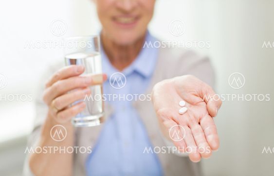 close up of senior woman with water and pills