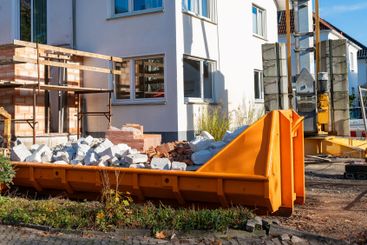 Daylight construction site with orange dumpster, materials