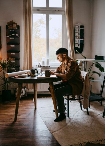 Young male freelancer working on laptop while sitting at...