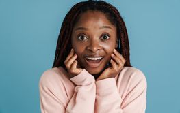 Young black woman with afro pigtails expressing surprise...