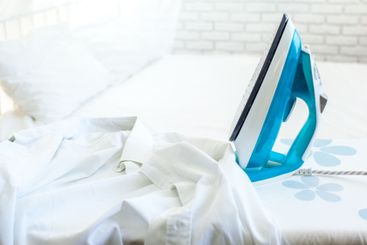 Iron on ironing board on light home interior background