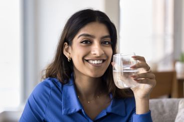 Beautiful Indian woman holding glass of mineral water