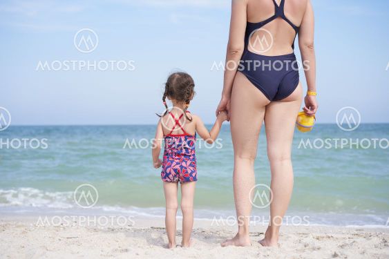 Mother daughter beach together rear view Unrecognizable...