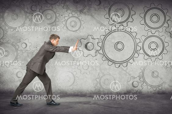 Businessman pushing cog wheels