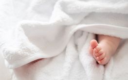 Innocence unveiled: newborn's foot peeking through white...