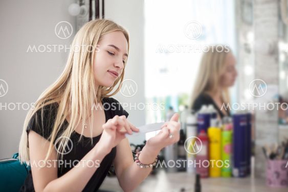 A woman is caring for her nails while sitting near a...