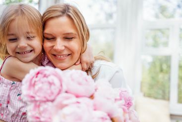 Embrace of a sweet girl and her happy smiling mom....