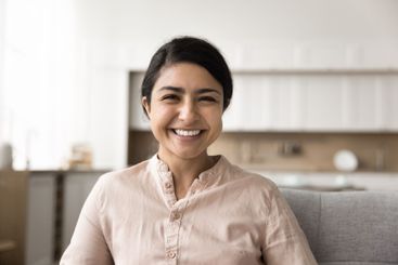 Smiling young woman sitting on sofa looking at camera