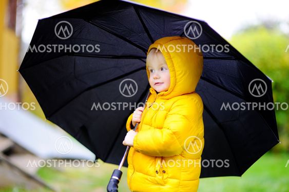 Child with big black umbrella in the rain