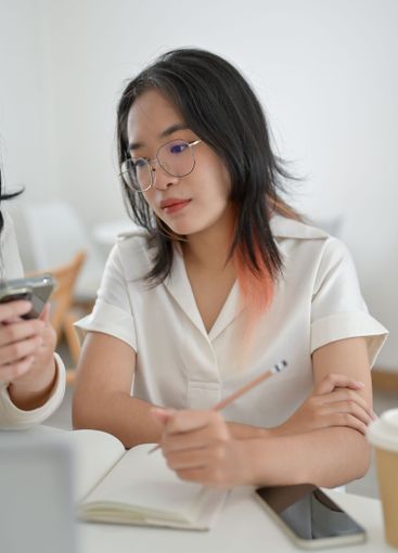 A serious Asian woman is concentrating on studying with...