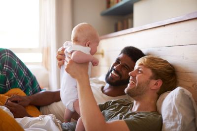 Loving Male Same Sex Couple Cuddling Baby Daughter In...