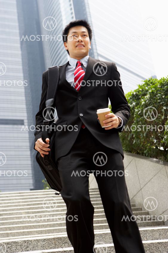 Chinese Businessman Rushing Down Steps Carrying Bag And Takeaway Coffee