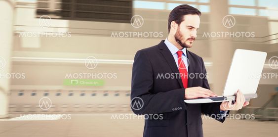 Composite image of focused businessman using his laptop