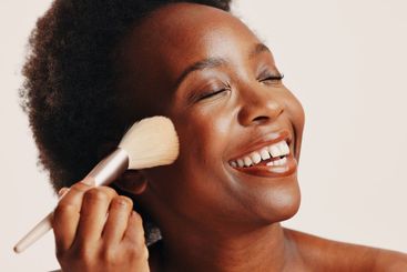 Brush, powder and black woman in studio with face,...
