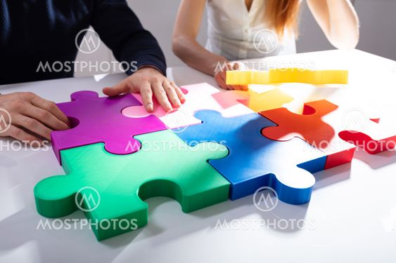 Two Businesspeople Solving Jigsaw Puzzle