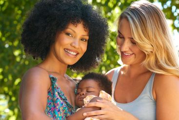 Loving Same Sex Female Couple Or Friends Cuddling Baby...